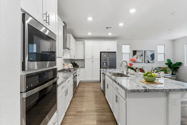 a kitchen with stainless steel appliances granite countertop a sink and a refrigerator