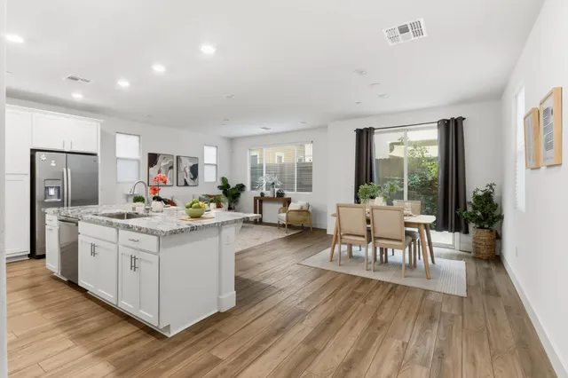 a living room with stainless steel appliances furniture a rug and a kitchen view