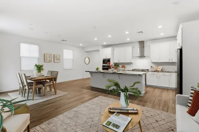 a kitchen with stainless steel appliances granite countertop a sink dishwasher a refrigerator and white cabinets with wooden floor