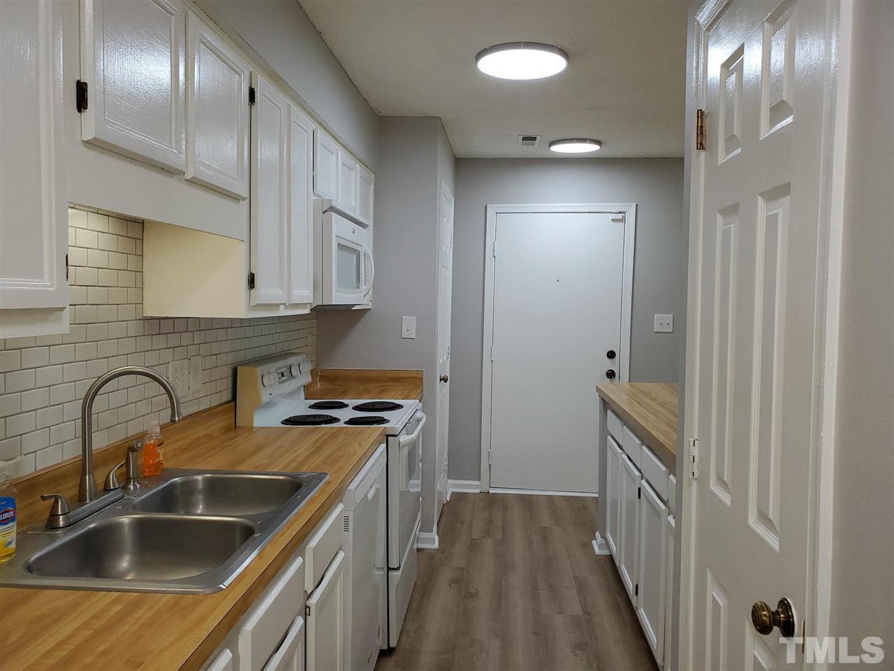 2011 Quaker Landing, Unit 103 Raleigh, NC 27603 - Photo 6 of 11 So much cabinet and counter space in this condo! The door to the right is a pantry for even more storage. The white cabinets and tile backsplash look so fresh and crisp against the light grey paint