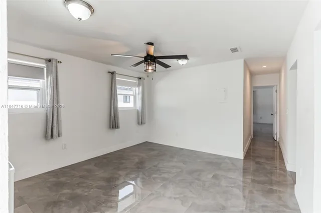 an empty room with windows and fan