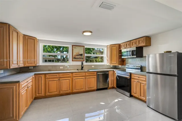 a kitchen with stainless steel appliances granite countertop a refrigerator a stove a sink and a microwave