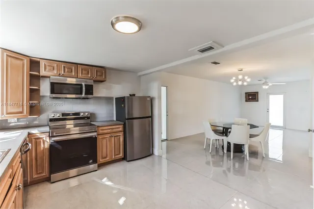 a kitchen with stainless steel appliances granite countertop a stove top oven a sink dishwasher a dining table and chairs