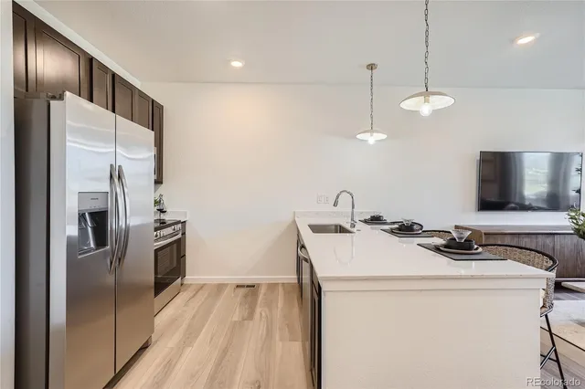 a kitchen that has a sink a refrigerator and a stove top oven