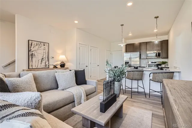 a living room with furniture kitchen and a wooden floor