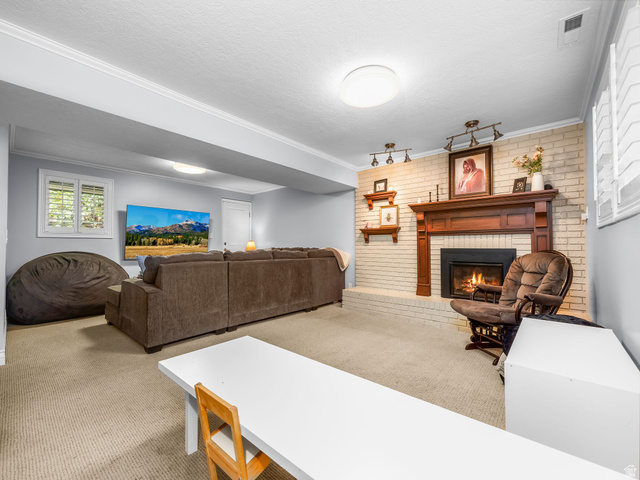 523 Mountain View Road Centerville, UT 84014 - Photo 18 of 33 Living area featuring carpet, brick wall, a brick fireplace, crown molding, and a textured ceiling