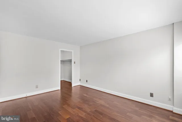 an empty room with wooden floor and window