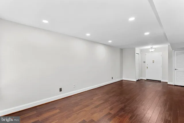 an empty room with wooden floor and natural light