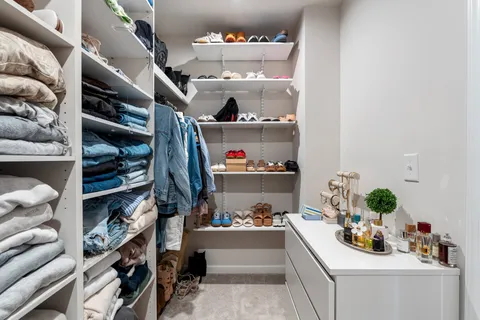 a view of walk in closet with clothes and shoes
