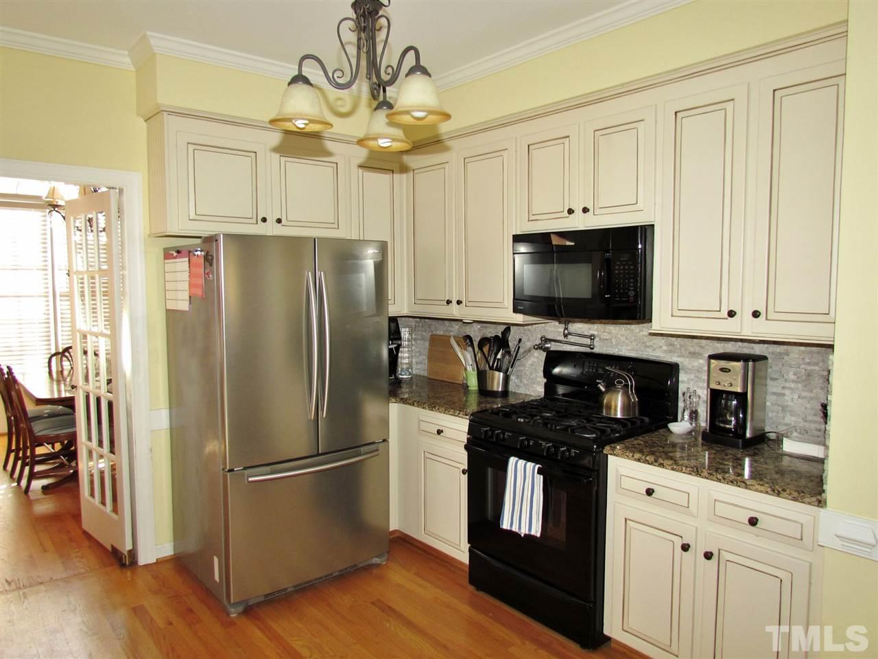 513 Tufts Court Raleigh, NC 27609 - Photo 9 of 25 a kitchen with a refrigerator stove and white cabinets