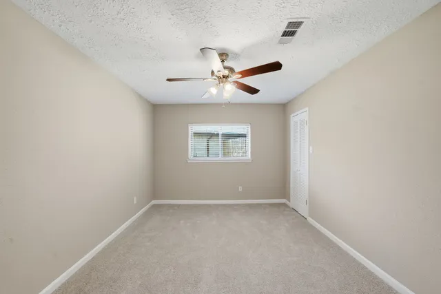 an empty room with a window and a fan
