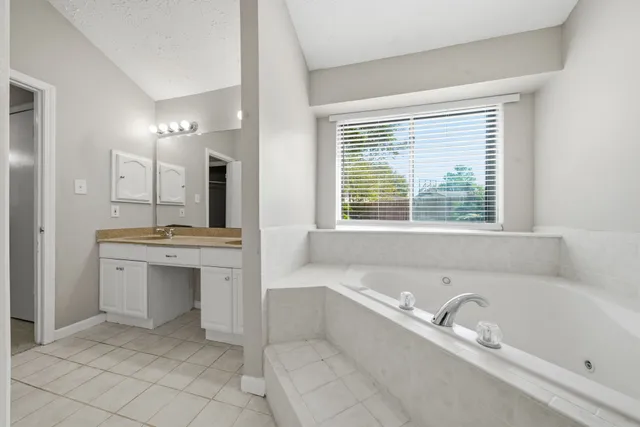 a bathroom with a bathtub a sink a mirror and a shower