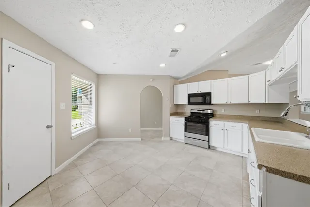 a large kitchen with a large counter top stainless steel appliances and cabinets