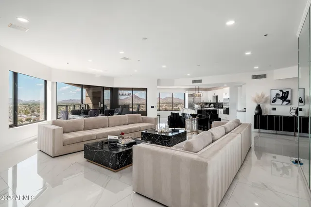 a living room with furniture a floor to ceiling window and kitchen view