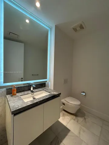 a bathroom with a granite countertop sink toilet and mirror