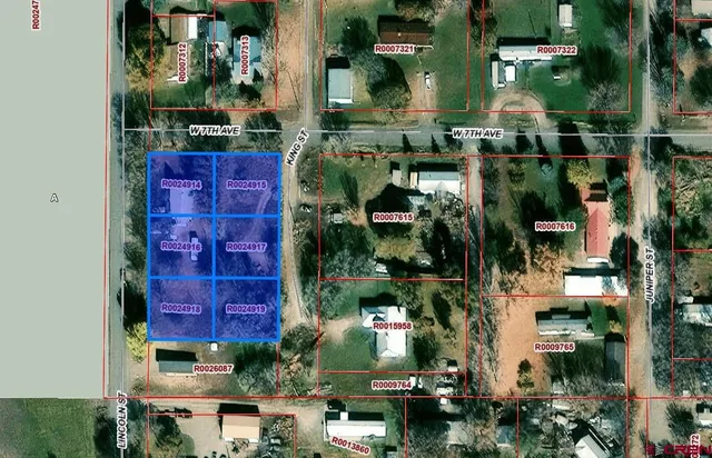 an aerial view of residential houses with outdoor space and trees all around