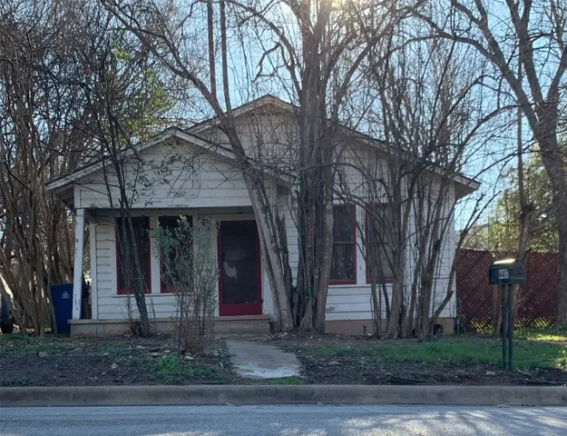 a front view of a house with trees and plants