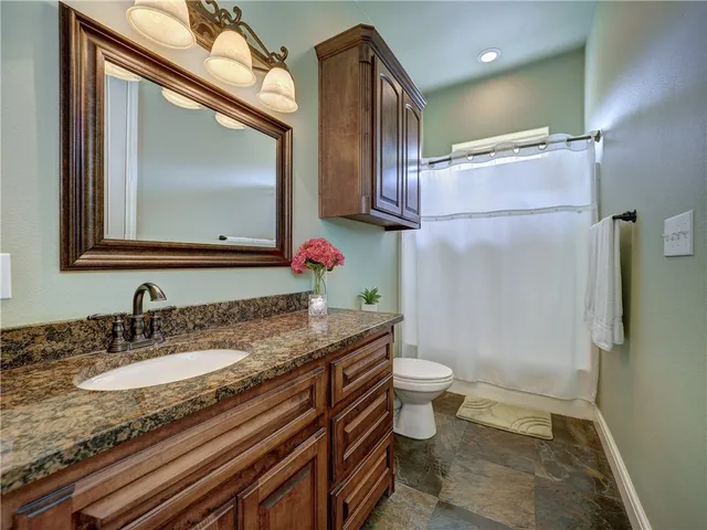 a bathroom with a granite countertop sink a mirror and a toilet