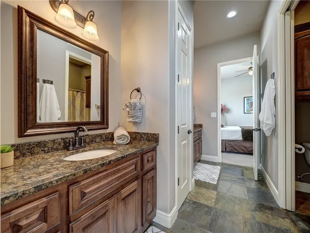 a en suite bathroom with a granite countertop sink and a mirror