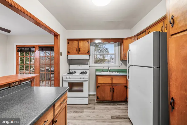 a kitchen with stainless steel appliances granite countertop a refrigerator a stove and a sink with large window