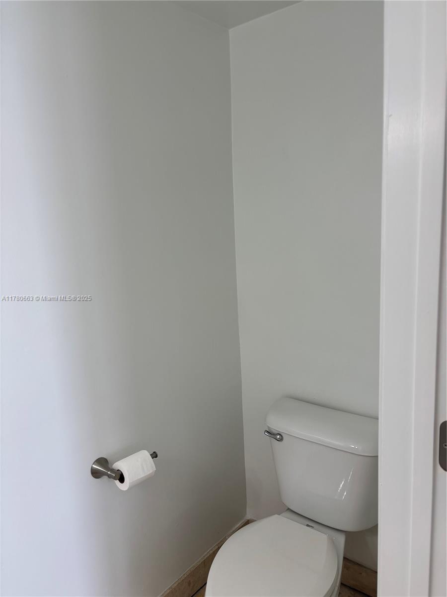 2415 Northwest 16th St Road, Unit 103 Miami, FL 33125 - Photo 13 of 42 a white toilet sitting next to a white wall