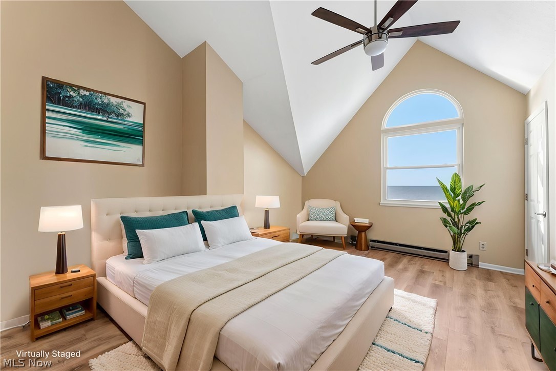 13011 West Lake Road Vermilion, OH 44089 - Photo 22 of 29 Bedroom featuring a vaulted ceiling with a ceiling fan, wood-finish flooring, and a large arched window
