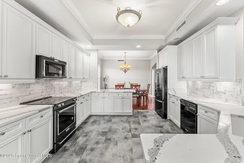 a large kitchen with a stove top oven a sink dishwasher a refrigerator and white cabinets with wooden floor