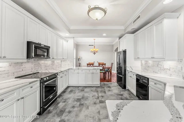 a large kitchen with a stove top oven a sink dishwasher a refrigerator and white cabinets with wooden floor