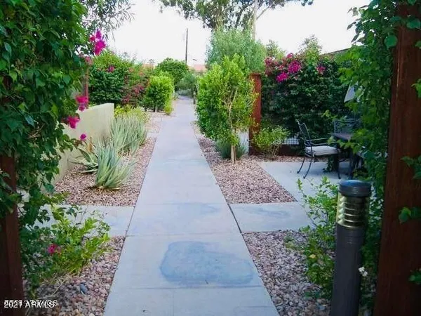 a pathway of a house with a yard and potted plants