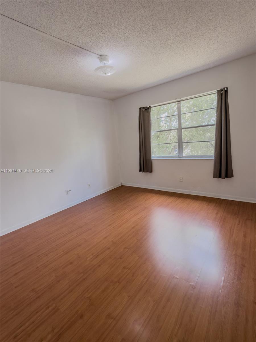 8411 Northwest 8th Street, Unit 301 Miami, FL 33126 - Photo 10 of 15 a view of an empty room with wooden floor and a window