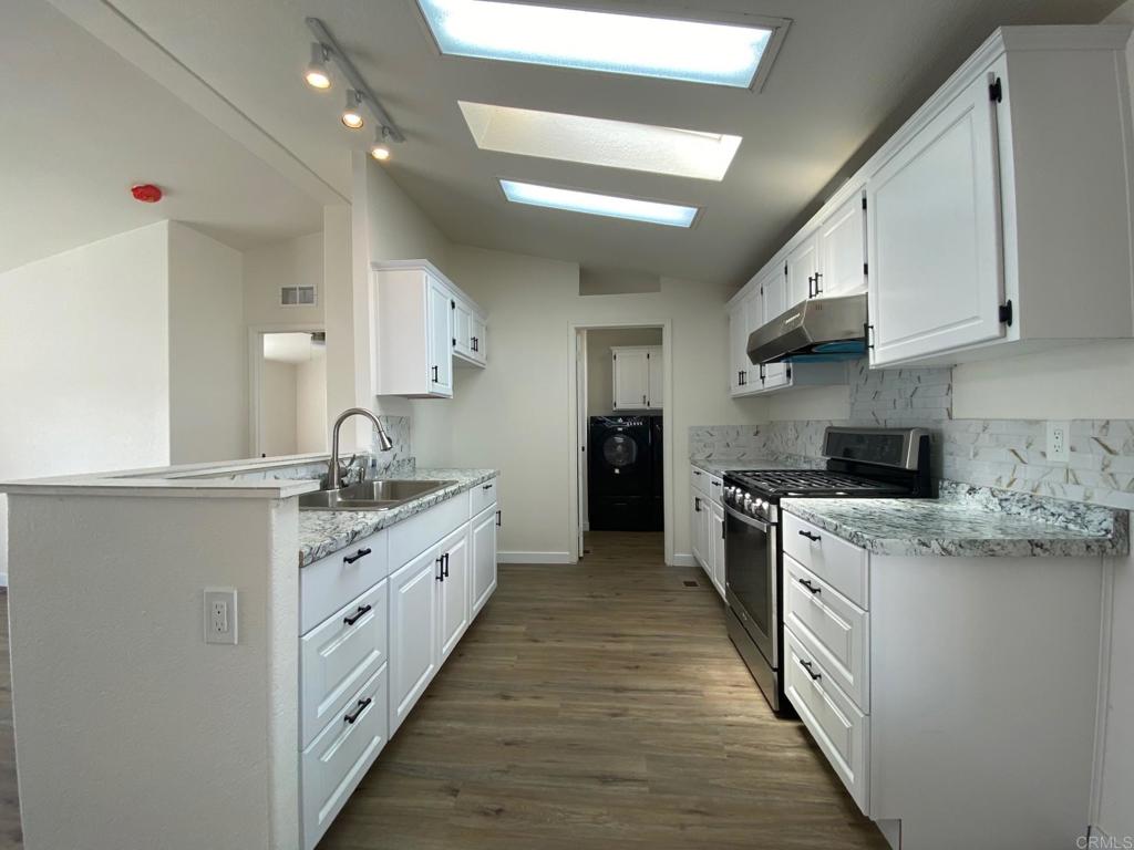 a large kitchen with stainless steel appliances granite countertop a lot of counter space and wooden floors