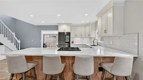 a kitchen with kitchen island granite countertop a dining table chairs and white cabinets