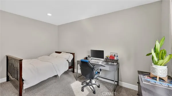 a bedroom with a bed table chair and a window