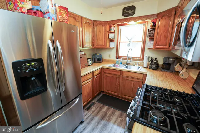 a kitchen with stainless steel appliances a refrigerator a sink a stove and cabinets