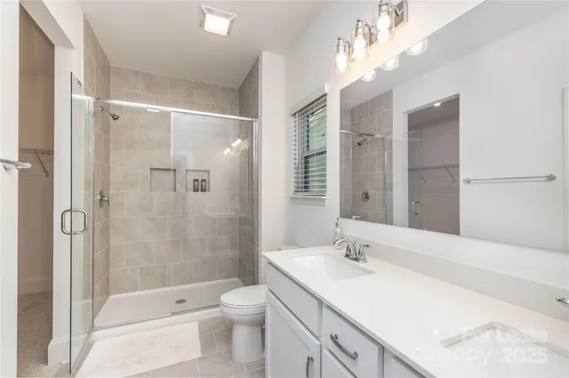 a bathroom with a granite countertop sink a toilet a mirror and shower