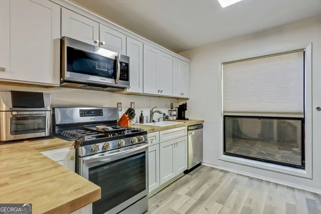a kitchen with stainless steel appliances a stove a microwave a sink and cabinets