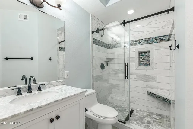a bathroom with a granite countertop sink toilet and shower