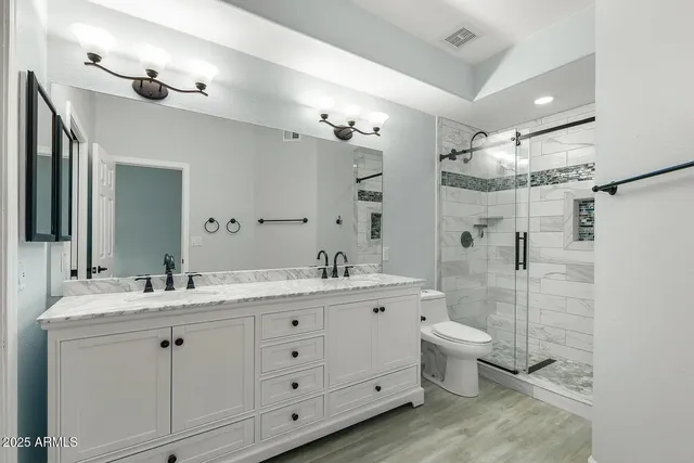 a bathroom with a double vanity sink toilet mirror and shower