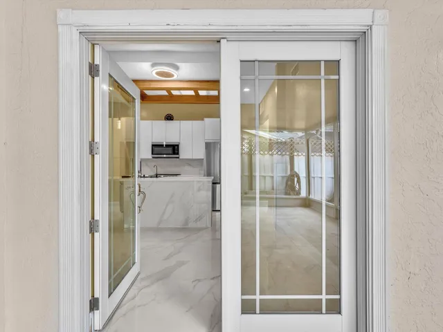 a kitchen with stainless steel appliances a sink a stove a refrigerator a microwave with white cabinets and wooden floor