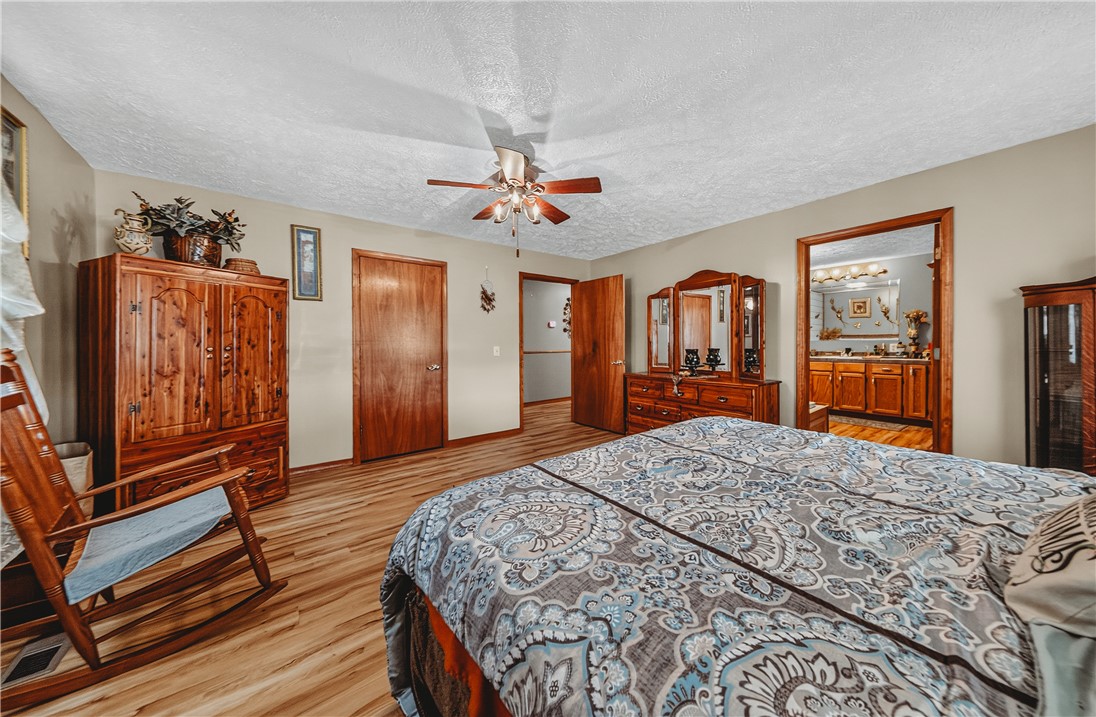 21587 West Hickory Flat Road Springdale, AR 72764 - Photo 25 of 45 Additional primary-bedroom view highlighting the room’s generous size, closet storage, wood flooring, and direct access to the primary bathroom.