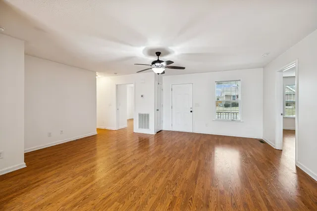 a view of an empty room with wooden floor and a window