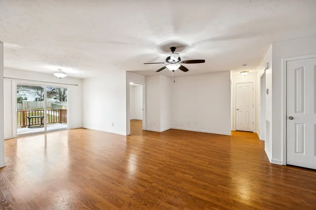 a view of an empty room with a window and wooden floor