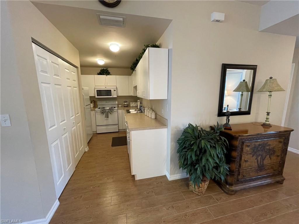 519 Roma Court, Unit 2103 Naples, FL 34110 - Photo 8 of 27 a kitchen with stainless steel appliances a refrigerator a sink a stove and wooden floor
