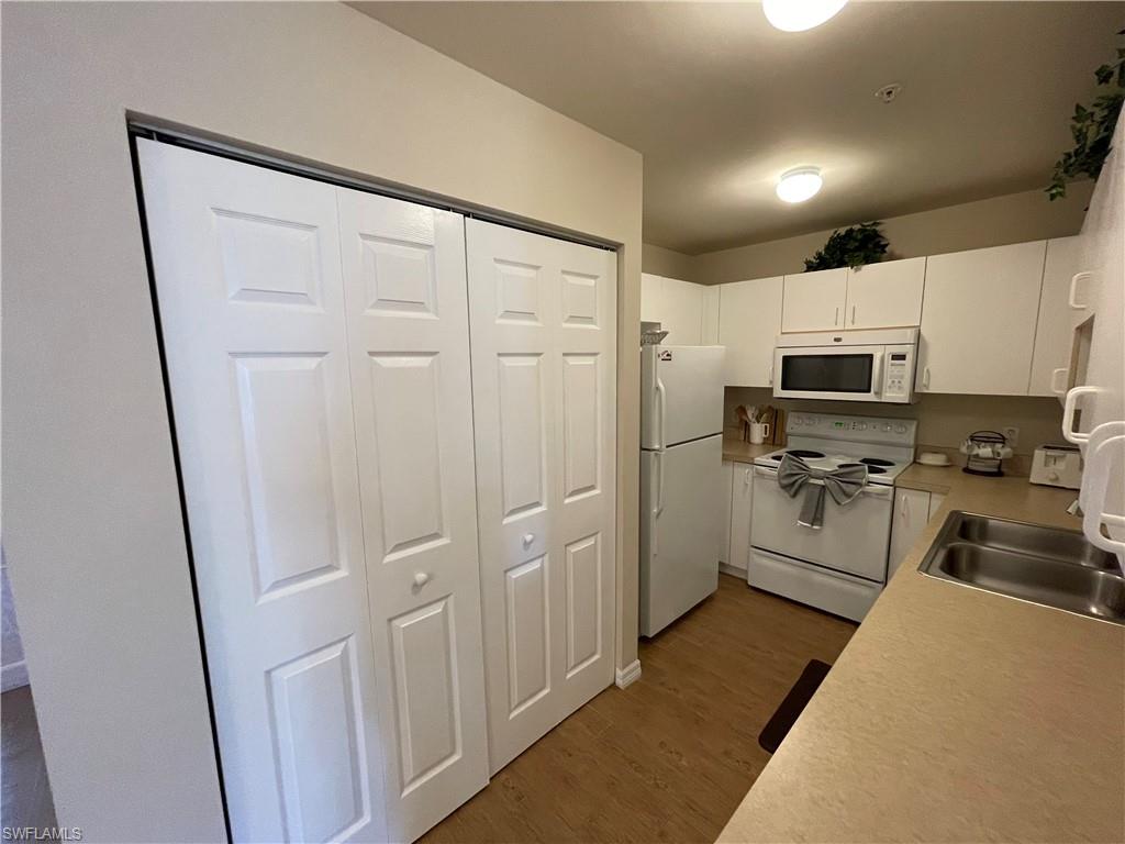 519 Roma Court, Unit 2103 Naples, FL 34110 - Photo 10 of 27 a kitchen with white cabinets and stainless steel appliances