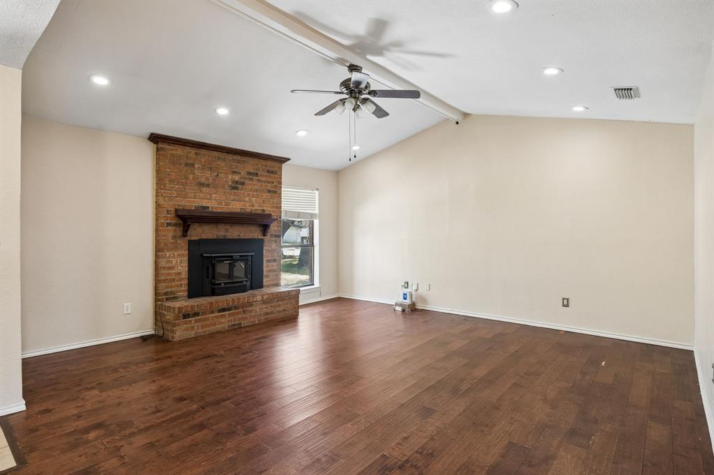 709 Bowie Street Forney, TX 75126 - Photo 2 of 27 an empty room with wooden floor fireplace and windows