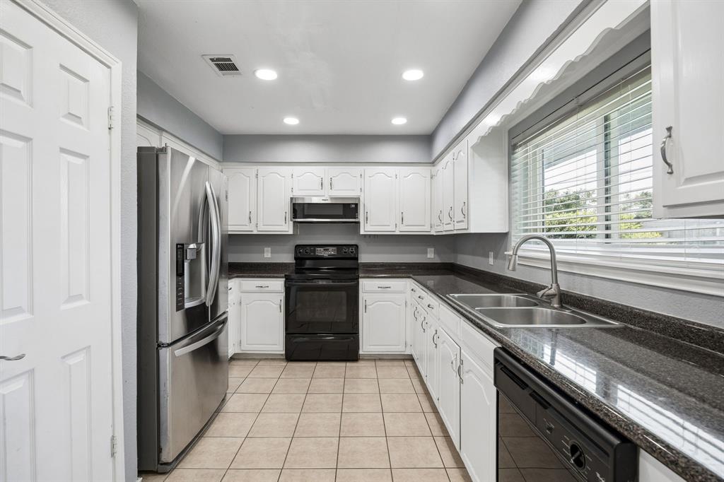 709 Bowie Street Forney, TX 75126 - Photo 3 of 27 a kitchen with a refrigerator a sink and wooden cabinets