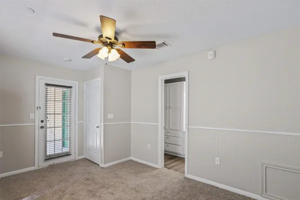 an empty room with windows and fan