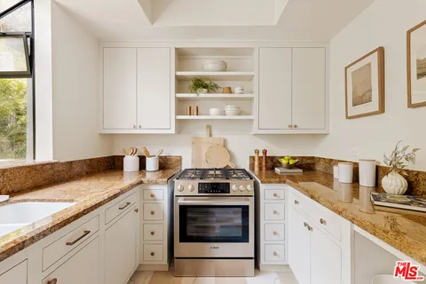 a kitchen with granite countertop white cabinets and white stainless steel appliances