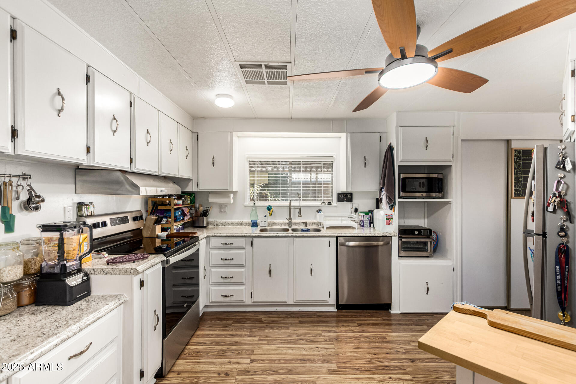 661 South Hawes Road, Unit 52 Mesa, AZ 85208 - Photo 6 of 36 a kitchen with stainless steel appliances kitchen island granite countertop a stove top oven a sink a refrigerator and white cabinets