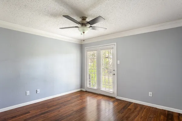 an empty room with wooden floor fan and windows